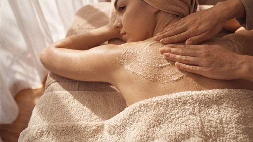 Body scrub and body butter arranged on linen